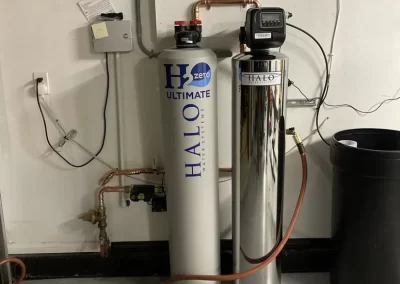 Two water filtration tanks labeled "HALO" and "H2zero" are installed in a utility room with pipes and wiring.