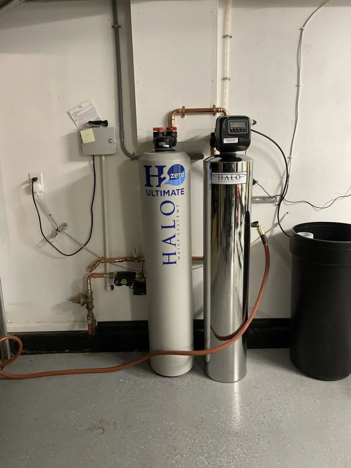 Two water filtration tanks labeled "HALO" installed against a wall with pipes and control panels.