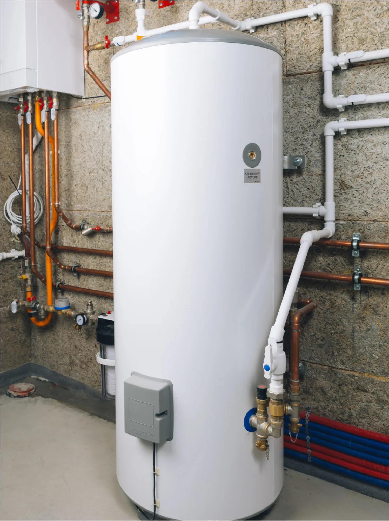 A white water heater tank in a utility room with pipes connected to it on the wall.